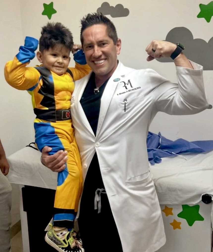 Dr. Morales posing as a super hero with a kid dressed in a superhero costume