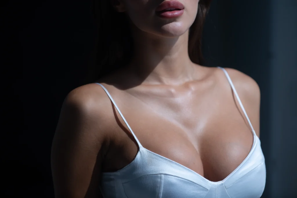A close-up of a woman's chest in a white satin camisole, highlighting her lifted and well-contoured breasts, representing the different types of breast lifts that can enhance shape, symmetry, and firmness for a youthful appearance.