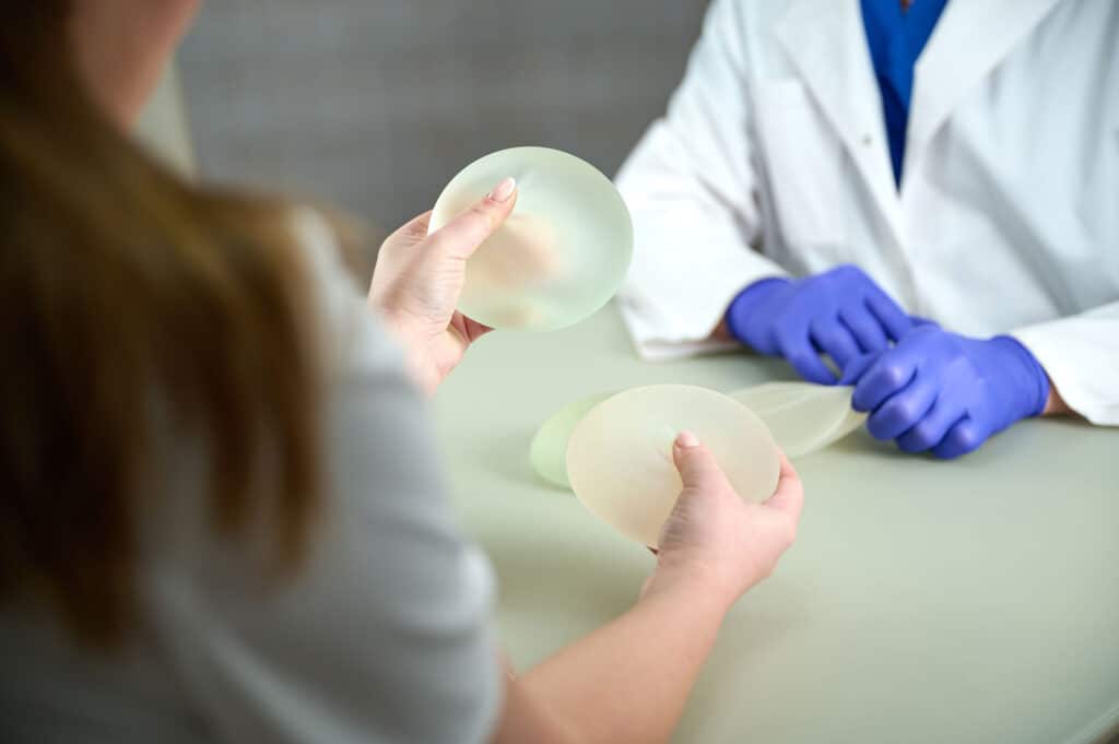 Patient holding silicone gel implants during a consultation to test if breast implants feel real.
